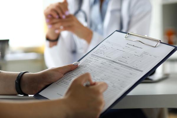 A patient filling out a form with their doctor.